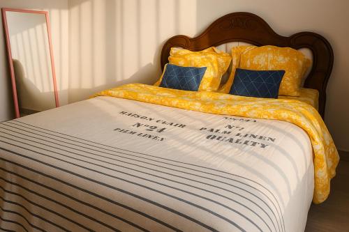 a bed with a yellow comforter and blue pillows at Ste Raphaelle Guest House in Yaoundé