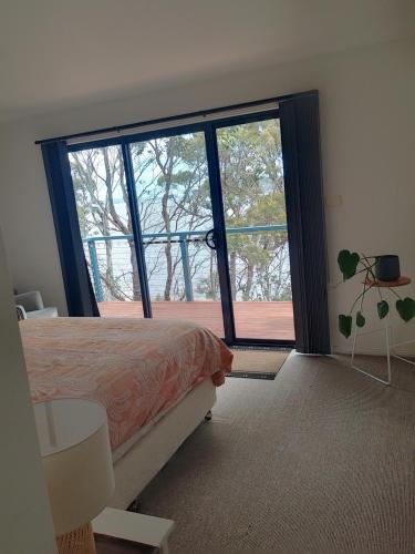 une chambre avec un lit et une grande fenêtre dans l'établissement The Cove, à Huon Island