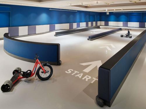 une salle d'exposition avec un vélo posé au sol à côté d'une table dans l'établissement Grand Mercure Yatsugatake Resort & Spa, à Hokuto