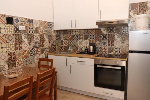 eine Küche mit weißen Schränken und einem Tisch mit Stühlen in der Unterkunft MOON RIVER - Rooms & Apartments in Castellammare di Stabia