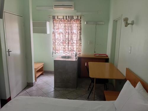 una camera da letto con un letto, un lavandino e un tavolo di Brackendene Lodge a Gaborone