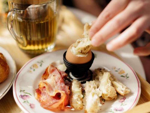 uma pessoa comendo um ovo em um prato com comida em Square Lodge Hotel Accor - La Roche-sur-Yon em La Roche-sur-Yon