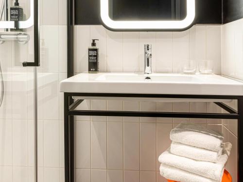 La salle de bains est pourvue d'un lavabo et d'un tas de serviettes. dans l'établissement ibis Styles Paris Villejuif, à Villejuif