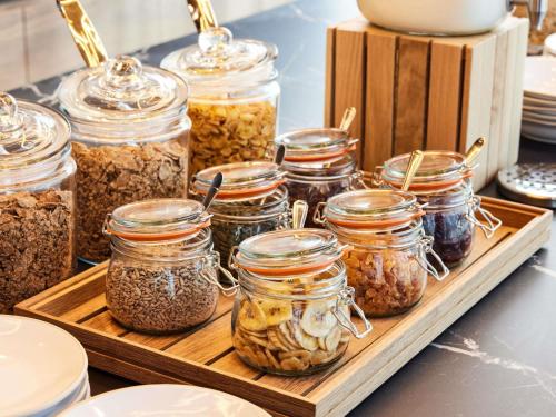 Ein Holztablett mit Gläsern voller Müsli auf einer Theke in der Unterkunft TRIBE Manchester Airport by Accor in Hale