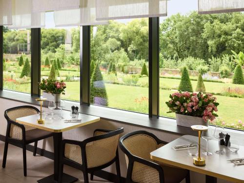 Un restaurante con mesas y sillas y un gran ventanal. en Domaine du Liziec Vannes - MGallery Collection, en Vannes