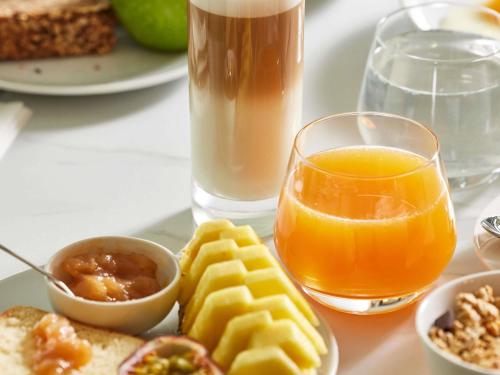 Un plato de desayuno con un vaso de zumo de naranja. en Domaine du Liziec Vannes - MGallery Collection, en Vannes