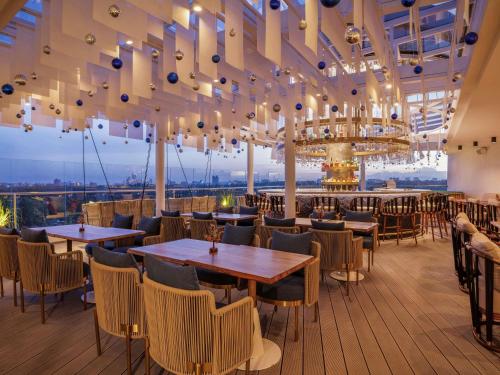 Un restaurante con mesas y sillas y una lámpara de araña. en Gem Forest Hotel Nairobi - MGallery Collection, en Nairobi