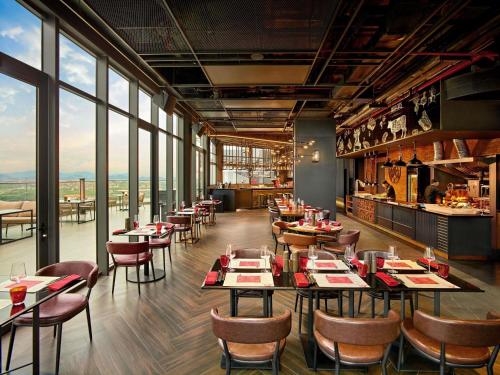 a restaurant with tables and chairs and windows at Pullman Hai Phong Grand Hotel in Hai Phong