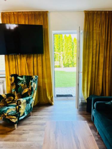 ein Wohnzimmer mit einem Stuhl und einer Glasschiebetür in der Unterkunft Apartament Sasankowa z bezpłatnym parkingiem in Lyck