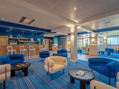 a waiting room with blue chairs and tables at ibis Styles Biarritz Plage in Biarritz