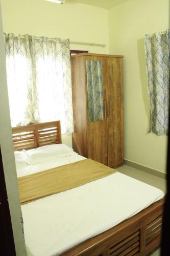 a bedroom with two beds and a wooden cabinet at Valley Homestay in Devikolam