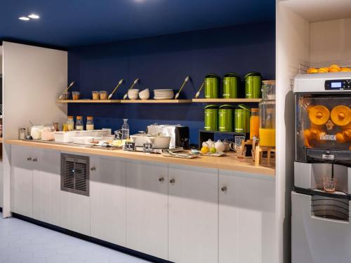 Una cocina con gabinetes blancos y ollas y sartenes verdes. en ibis budget Morlaix, en Morlaix