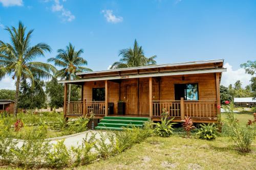 een klein houten huis met een veranda bij Signature Collections by Eight Continents in Utende