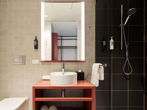 a bathroom with a sink and a mirror and a shower at ibis Styles Melbourne Airport in Melbourne