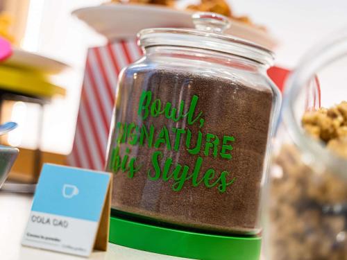 Un frasco con un cartel sobre una mesa. en ibis Styles Lisboa Aeroporto, en Lisboa