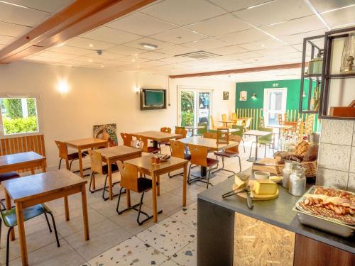 Un restaurante con mesas y sillas en una sala. en greet Hôtel Montbéliard, en Montbéliard