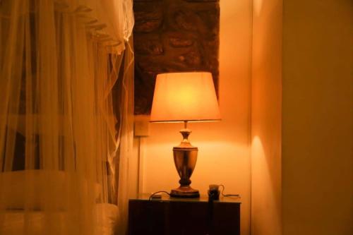 a lamp sitting on a table next to a bed at Skyhill Kandy in Hindagala