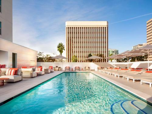 a swimming pool with lounge chairs and a hotel at Fairmont Breakers Long Beach in Long Beach