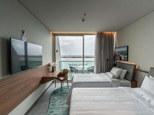 a hotel room with two beds and a balcony at Novotel Recife Marina in Recife