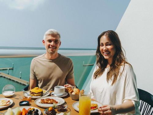 Un hombre y una mujer sentados en una mesa con comida. en Novotel Recife Marina, en Recife
