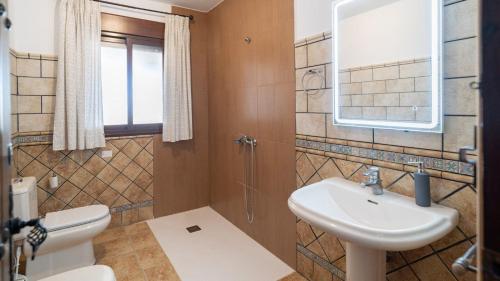 Un baño con lavabo, inodoro y espejo. en Finca Las Hoyas Loja by Ruralidays, en Cuesta de la Palma