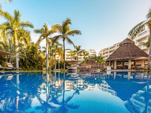 una piscina in un resort con palme di Marival Distinct All-Suites & World Spa - Handwritten Collection a Nuevo Vallarta