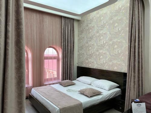 Un dormitorio con una cama con una ventana grande. en Hotel Roma & Tours, en Ereván
