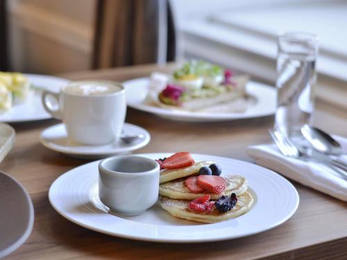 a table with plates of pancakes and cups of coffee at The Mozart Prague in Prague