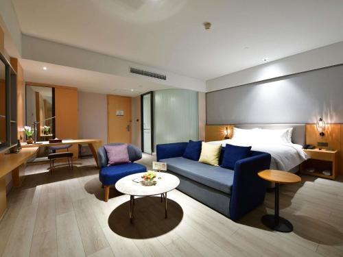 une chambre d'hôtel avec un canapé et un lit dans l'établissement Mercure Qidong Downtown, à Qidong