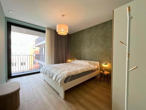 une chambre avec un lit et une grande fenêtre dans l'établissement Appartement moderne 2 chambres & 2 parking à Koksijde by La Conciergerie, à Coxyde
