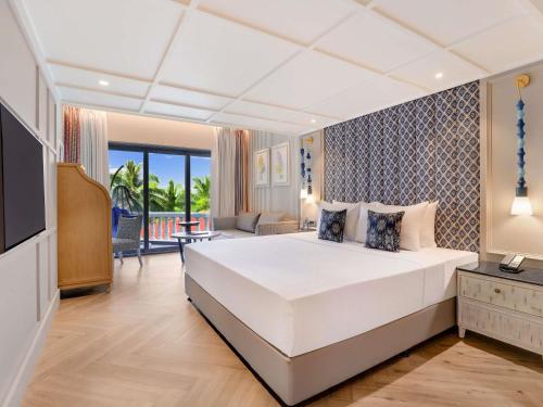 Un dormitorio con una gran cama blanca y un balcón. en Grand Mercure Goa Candolim - An Accor Hotels Brand, en Candolim
