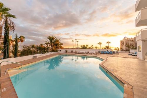 Una piscina con una puesta de sol al fondo en Apart hotel Ponderosa with a pool & view, studio 226, en Playa Fañabe