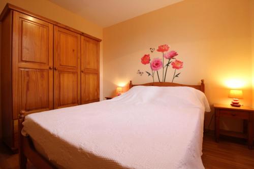 - une chambre avec un lit blanc et des fleurs sur le mur dans l'établissement Appartement Le Chalet Vert proche lac randonnées, à La Bresse