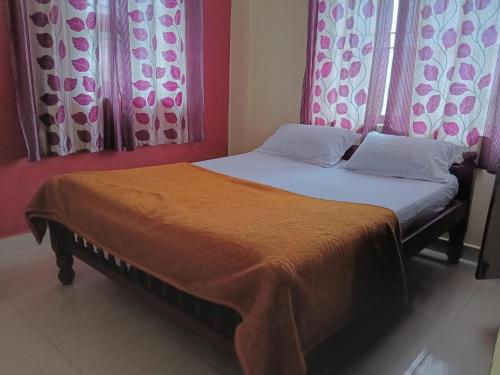 a bed with two pillows and a orange blanket at Coorg villas & homes in Madikeri