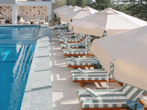 a row of lounge chairs with umbrellas next to a pool at Mondrian Gold Coast in Gold Coast