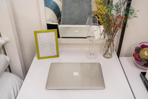 una mesa blanca con un ordenador portátil, vasos y flores en Bến Thành Market - KAS HOTEL, en Ho Chi Minh