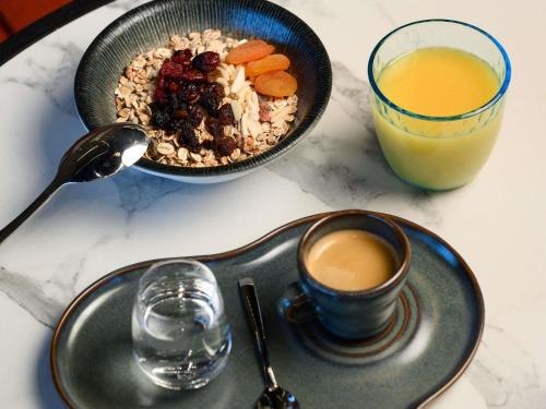 a plate with a bowl of cereal and a glass of orange juice at TRIBE Budapest Airport in Budapest
