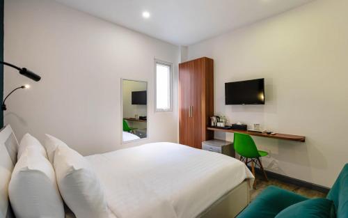 a bedroom with a white bed and a green chair at LeParc Hotel - Ben Thanh Market in Ho Chi Minh City