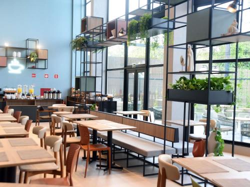 un restaurant avec des tables, des chaises et des fenêtres dans l'établissement ibis Tangará Da Serra, à Tangará da Serra