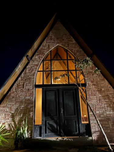 a building with a large window and a black door at O Canto das Fadas Chalés in São Thomé das Letras