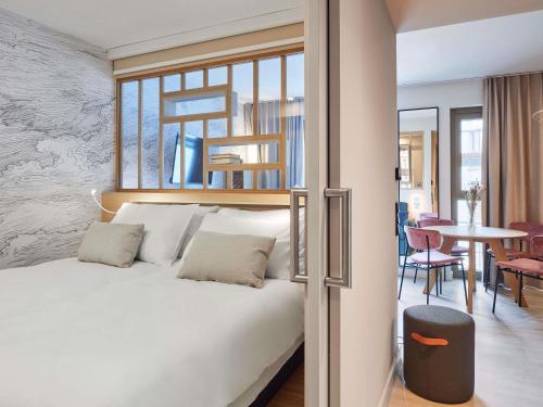 Un dormitorio con una cama y una mesa con sillas. en Aparthotel Adagio Stuttgart NeckarPark, en Stuttgart