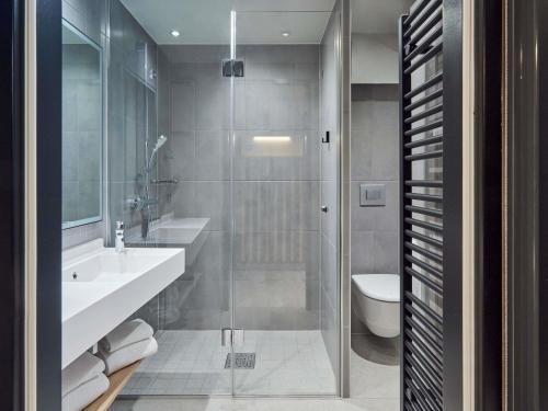 Un baño con ducha, lavabo e inodoro. en Aparthotel Adagio Stuttgart NeckarPark, en Stuttgart
