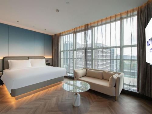 a bedroom with a bed and a couch and a table at Novotel Shanghai Lingang in Nanhui
