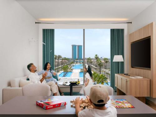 une famille assise dans un salon avec vue sur une piscine dans l'établissement Rixos Obhur Jeddah Resort & Villas - All-Inclusive, à Djeddah