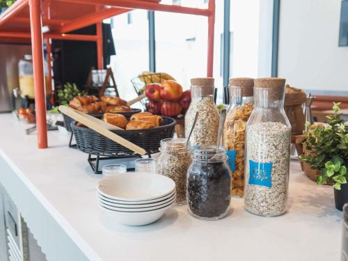 um balcão com várias garrafas de vidro cheias de comida em ibis budget Madrid Albasanz em Madrid