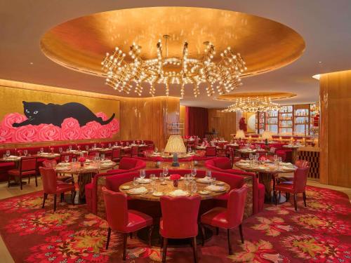 a restaurant with tables and red chairs and a chandelier at Faena New York in New York