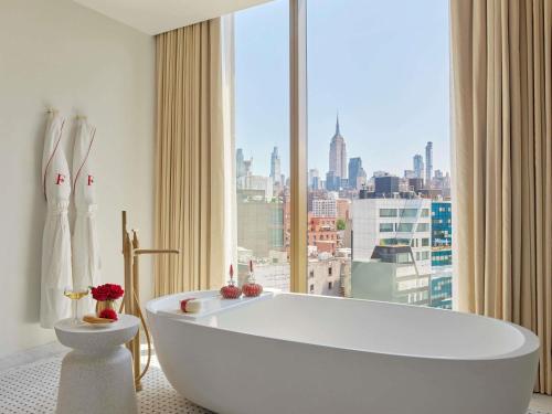 Una bañera blanca en una habitación con ventana. en Faena New York, en Nueva York