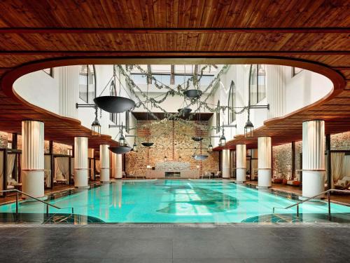 a large swimming pool in a building with a wooden ceiling at Aliée Istanbul - A Paris Society Collection Hotel in Istanbul
