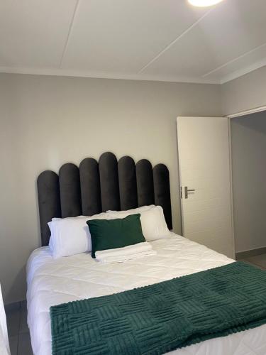 ein großes Bett mit einem schwarzen gepolsterten Kopfteil in einem Zimmer in der Unterkunft Unmatched Stays in Kempton Park