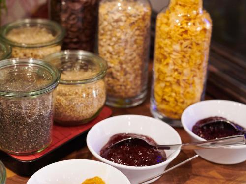 une table avec des bocaux de graines et des bols de confitures dans l'établissement Greet Hôtel Saint-Nazaire Trignac Nouvelle Marque du Groupe Accor, à Trignac